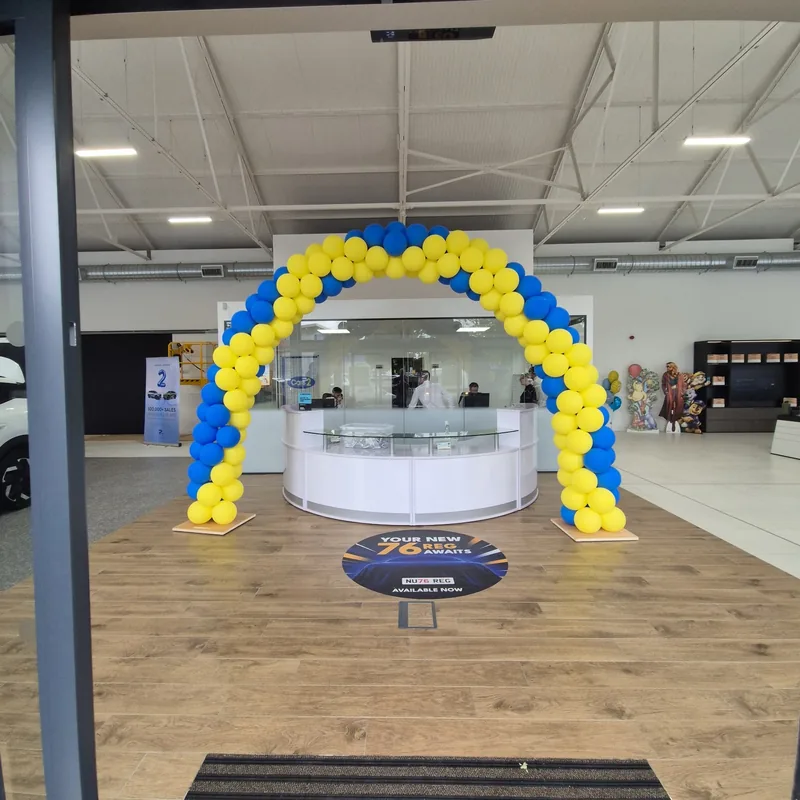 Blue and yellow indoor balloon arch in a car showroom